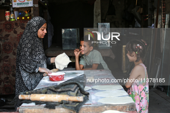 A displaced Palestinian woman is preparing flatbread dough at a stall kitchen in Deir el-Balah in the central Gaza Strip on July 2, 2024, am...