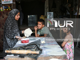 A displaced Palestinian woman is preparing flatbread dough at a stall kitchen in Deir el-Balah in the central Gaza Strip on July 2, 2024, am...