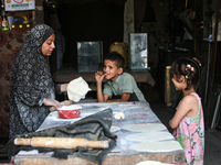 A displaced Palestinian woman is preparing flatbread dough at a stall kitchen in Deir el-Balah in the central Gaza Strip on July 2, 2024, am...