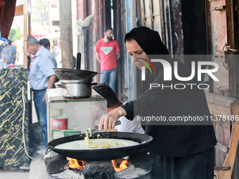 A displaced Palestinian woman is frying falafel at a stall in Deir el-Balah in the central Gaza Strip on July 2, 2024, amid the ongoing conf...