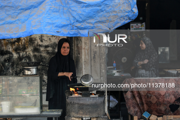 A displaced Palestinian woman is frying falafel at a stall in Deir el-Balah in the central Gaza Strip on July 2, 2024, amid the ongoing conf...