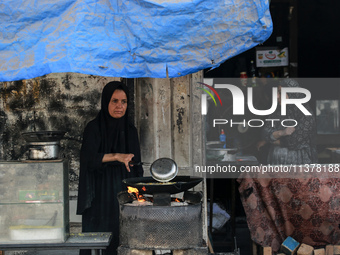 A displaced Palestinian woman is frying falafel at a stall in Deir el-Balah in the central Gaza Strip on July 2, 2024, amid the ongoing conf...