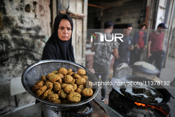 A displaced Palestinian woman is frying falafel at a stall in Deir el-Balah in the central Gaza Strip on July 2, 2024, amid the ongoing conf...