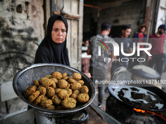 A displaced Palestinian woman is frying falafel at a stall in Deir el-Balah in the central Gaza Strip on July 2, 2024, amid the ongoing conf...