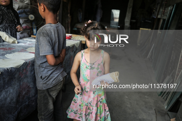 A displaced Palestinian woman is preparing flatbread dough at a stall kitchen in Deir el-Balah in the central Gaza Strip on July 2, 2024, am...