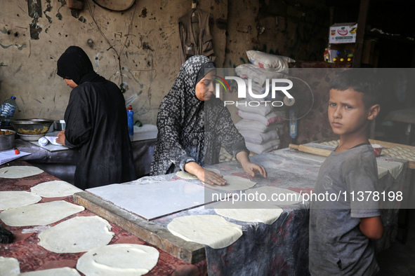 A displaced Palestinian woman is preparing flatbread dough at a stall kitchen in Deir el-Balah in the central Gaza Strip on July 2, 2024, am...