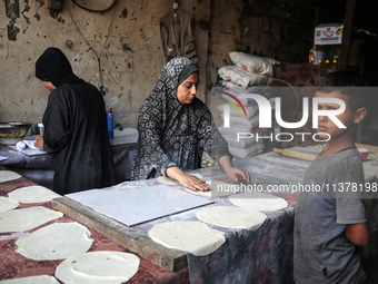 A displaced Palestinian woman is preparing flatbread dough at a stall kitchen in Deir el-Balah in the central Gaza Strip on July 2, 2024, am...