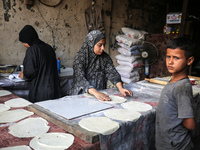 A displaced Palestinian woman is preparing flatbread dough at a stall kitchen in Deir el-Balah in the central Gaza Strip on July 2, 2024, am...