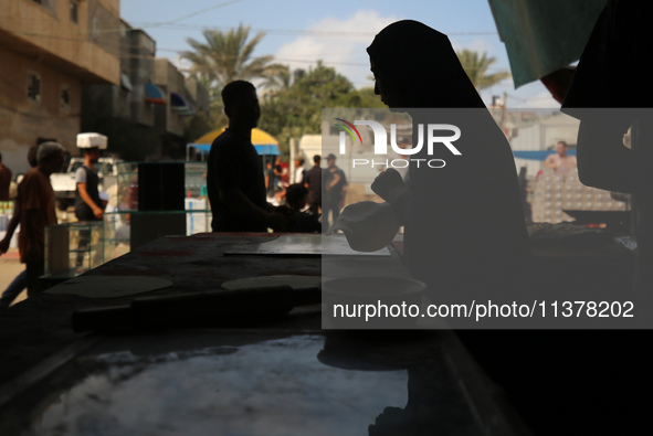 A displaced Palestinian woman is preparing flatbread dough at a stall kitchen in Deir el-Balah in the central Gaza Strip on July 2, 2024, am...