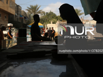 A displaced Palestinian woman is preparing flatbread dough at a stall kitchen in Deir el-Balah in the central Gaza Strip on July 2, 2024, am...