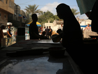 A displaced Palestinian woman is preparing flatbread dough at a stall kitchen in Deir el-Balah in the central Gaza Strip on July 2, 2024, am...