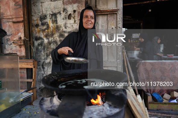 A displaced Palestinian woman is frying falafel at a stall in Deir el-Balah in the central Gaza Strip on July 2, 2024, amid the ongoing conf...