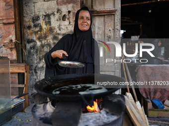 A displaced Palestinian woman is frying falafel at a stall in Deir el-Balah in the central Gaza Strip on July 2, 2024, amid the ongoing conf...