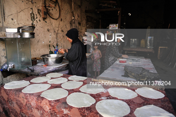 A displaced Palestinian woman is preparing flatbread dough at a stall kitchen in Deir el-Balah in the central Gaza Strip on July 2, 2024, am...