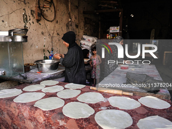 A displaced Palestinian woman is preparing flatbread dough at a stall kitchen in Deir el-Balah in the central Gaza Strip on July 2, 2024, am...