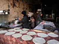 A displaced Palestinian woman is preparing flatbread dough at a stall kitchen in Deir el-Balah in the central Gaza Strip on July 2, 2024, am...