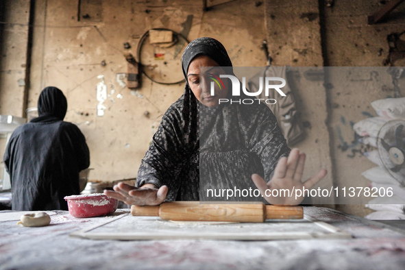 A displaced Palestinian woman is preparing flatbread dough at a stall kitchen in Deir el-Balah in the central Gaza Strip on July 2, 2024, am...