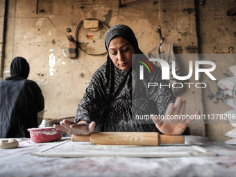 A displaced Palestinian woman is preparing flatbread dough at a stall kitchen in Deir el-Balah in the central Gaza Strip on July 2, 2024, am...