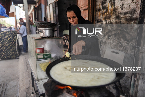 A displaced Palestinian woman is frying falafel at a stall in Deir el-Balah in the central Gaza Strip on July 2, 2024, amid the ongoing conf...