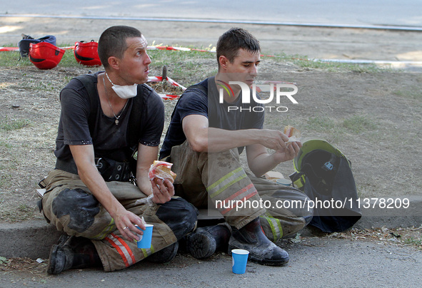 Rescuers are eating during a break as a response effort is underway at the apartment block hit by a Russian missile in Dnipro, Ukraine, on J...