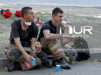 Rescuers are eating during a break as a response effort is underway at the apartment block hit by a Russian missile in Dnipro, Ukraine, on J...