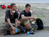 Rescuers are eating during a break as a response effort is underway at the apartment block hit by a Russian missile in Dnipro, Ukraine, on J...