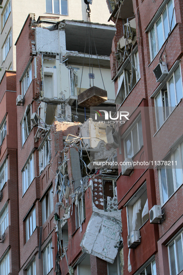 A crane and container are being used to remove the rubble at the apartment block hit by a Russian missile in Dnipro, Ukraine, on June 30, 20...