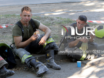 Rescuers are eating during a break as a response effort is underway at the apartment block hit by a Russian missile in Dnipro, Ukraine, on J...