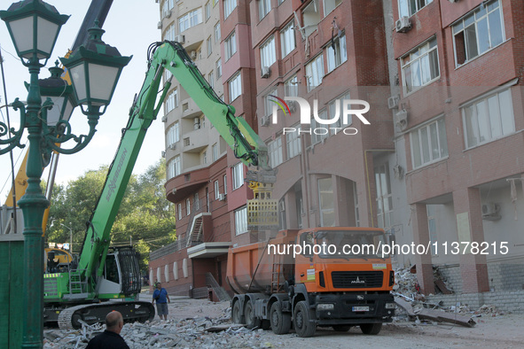 A crane and container are being used to remove the rubble at the apartment block hit by a Russian missile in Dnipro, Ukraine, on June 30, 20...