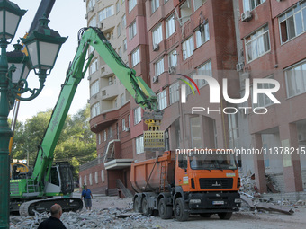 A crane and container are being used to remove the rubble at the apartment block hit by a Russian missile in Dnipro, Ukraine, on June 30, 20...