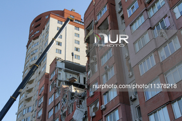 A crane and container are being used to remove the rubble at the apartment block hit by a Russian missile in Dnipro, Ukraine, on June 30, 20...