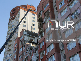 A crane and container are being used to remove the rubble at the apartment block hit by a Russian missile in Dnipro, Ukraine, on June 30, 20...