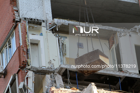 A crane and container are being used to remove the rubble at the apartment block hit by a Russian missile in Dnipro, Ukraine, on June 30, 20...