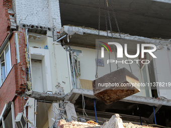 A crane and container are being used to remove the rubble at the apartment block hit by a Russian missile in Dnipro, Ukraine, on June 30, 20...