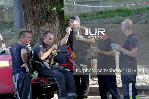 Rescuers are eating during a break as a response effort is underway at the apartment block hit by a Russian missile in Dnipro, Ukraine, on J...