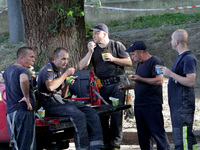 Rescuers are eating during a break as a response effort is underway at the apartment block hit by a Russian missile in Dnipro, Ukraine, on J...