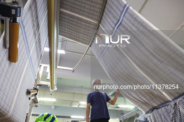 Workers are producing towel products for export at a workshop of a towel manufacturer in Binzhou, China, on July 2, 2024. 