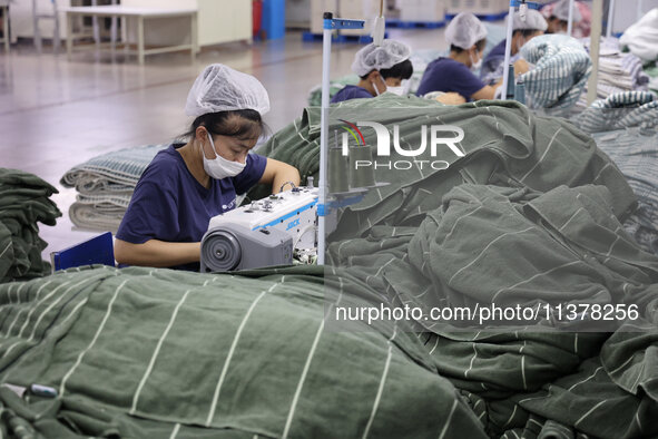 Workers are producing towel products for export at a workshop of a towel manufacturer in Binzhou, China, on July 2, 2024. 