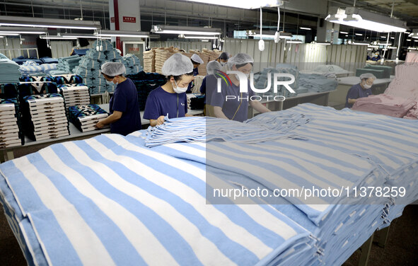 Workers are producing towel products for export at a workshop of a towel manufacturer in Binzhou, China, on July 2, 2024. 