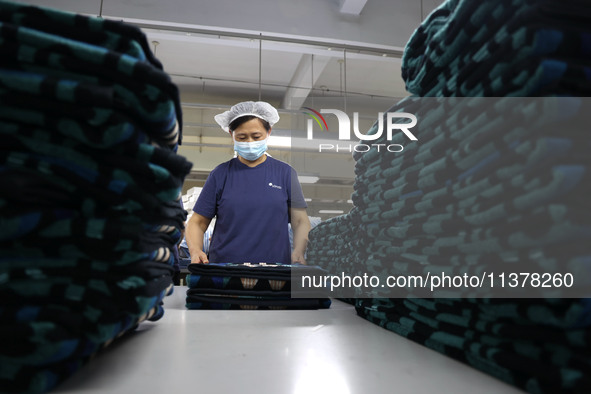 Workers are producing towel products for export at a workshop of a towel manufacturer in Binzhou, China, on July 2, 2024. 