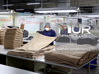 Workers are producing towel products for export at a workshop of a towel manufacturer in Binzhou, China, on July 2, 2024. (