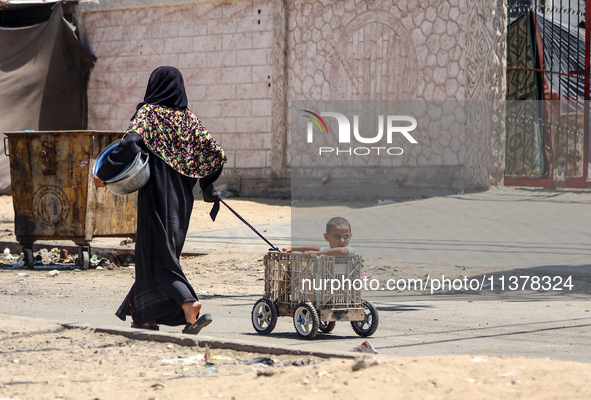 A Palestinian woman is walking in the street and dragging her son in Deir el-Balah, in the central Gaza Strip, on July 2, 2024, amid the ong...