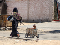 A Palestinian woman is walking in the street and dragging her son in Deir el-Balah, in the central Gaza Strip, on July 2, 2024, amid the ong...