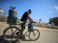 A Palestinian man is riding a bicycle carrying a gas canister in Deir el-Balah in the central Gaza Strip on July 2, 2024, amid the ongoing c...