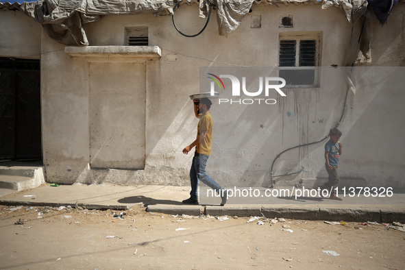 A Palestinian seller is carrying sweets as he is walking in Deir el-Balah in the central Gaza Strip on July 2, 2024, amid the ongoing confli...