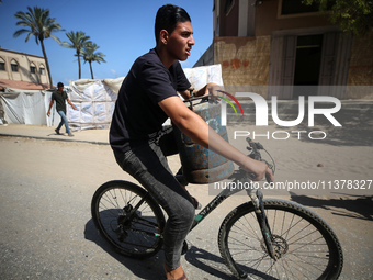 A Palestinian man is riding a bicycle carrying a gas canister in Deir el-Balah in the central Gaza Strip on July 2, 2024, amid the ongoing c...