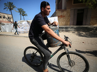 A Palestinian man is riding a bicycle carrying a gas canister in Deir el-Balah in the central Gaza Strip on July 2, 2024, amid the ongoing c...