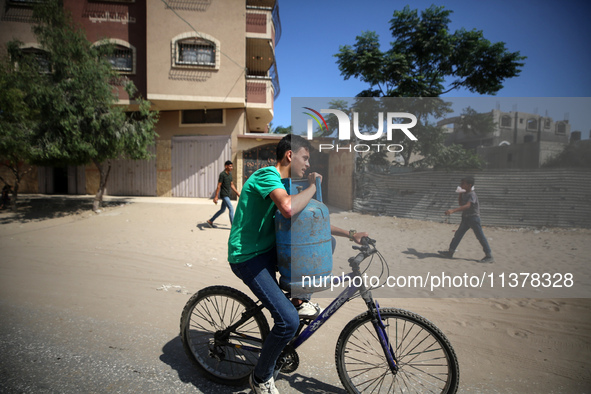 A Palestinian man is riding a bicycle carrying a gas canister in Deir el-Balah in the central Gaza Strip on July 2, 2024, amid the ongoing c...