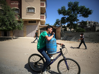 A Palestinian man is riding a bicycle carrying a gas canister in Deir el-Balah in the central Gaza Strip on July 2, 2024, amid the ongoing c...