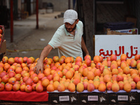 A produce merchant is arranging mangoes for sale at a stall along a market street in Deir el-Balah in the central Gaza Strip on July 2, 2024...